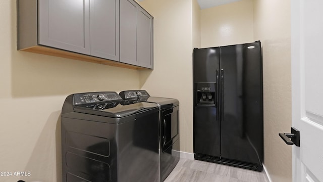 clothes washing area featuring washer and dryer and cabinets