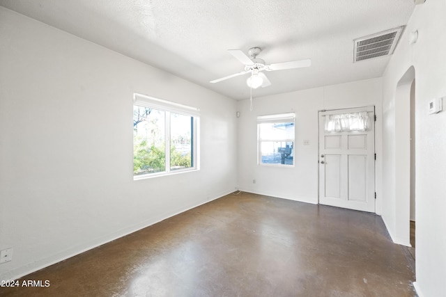 unfurnished room with ceiling fan and a textured ceiling