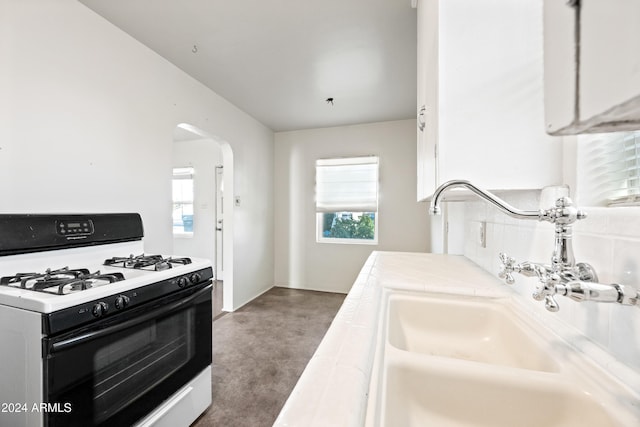 kitchen with white cabinetry, a wealth of natural light, white gas stove, and sink