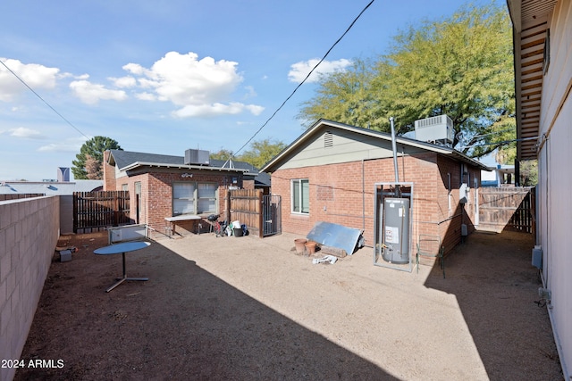 back of house with gas water heater and central AC