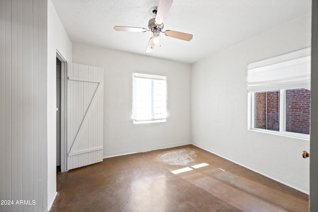 unfurnished bedroom with a textured ceiling, ceiling fan, and wooden walls