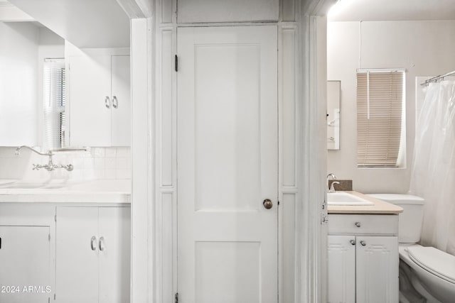 bathroom with curtained shower, vanity, and toilet