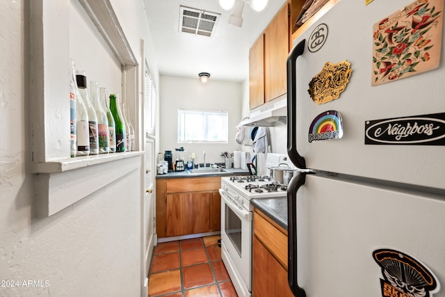 kitchen with white appliances, dark tile patterned floors, and sink