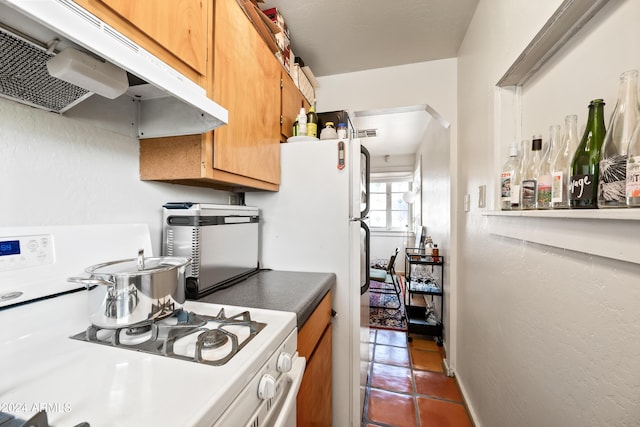 kitchen with white stove and dark tile patterned floors