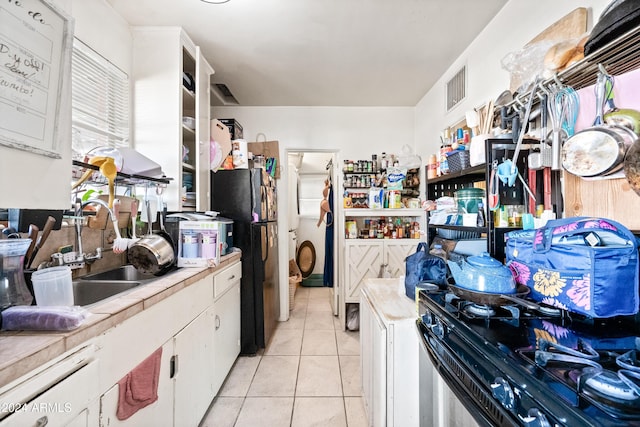 kitchen featuring white cabinets, light tile patterned floors, and black appliances