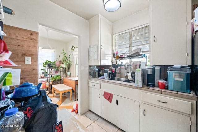 kitchen with white cabinets, decorative light fixtures, light tile patterned floors, and sink