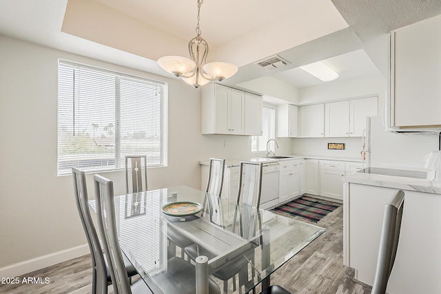 4554 E Paradise Village Pkwy N Unit 249, Phoenix, AZ 85032 - dining area with baseboards, light wood-style flooring, visible vents, and an inviting chandelier
