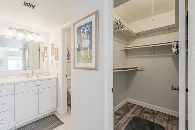 4554 E Paradise Village Pkwy N Unit 249, Phoenix, AZ 85032 - full bathroom featuring vanity, wood finished floors, a spacious closet, baseboards, and visible vents