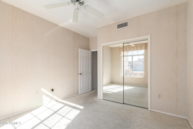 unfurnished bedroom featuring light carpet, a closet, and ceiling fan