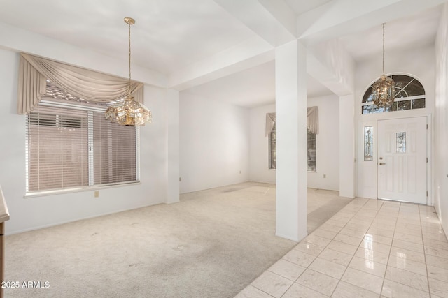 carpeted entrance foyer with an inviting chandelier