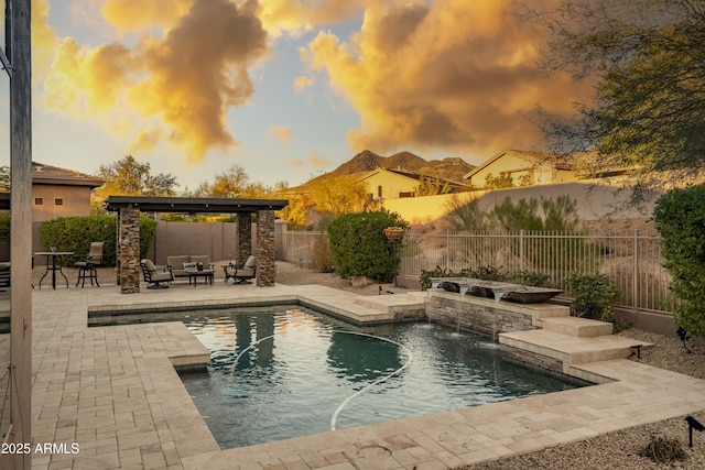 pool at dusk featuring pool water feature, an outdoor living space, and a patio