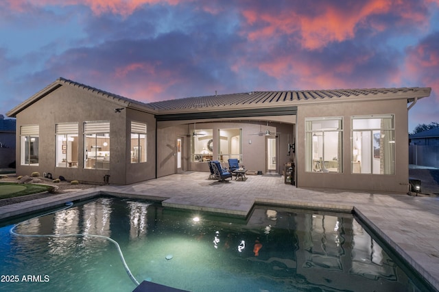 back house at dusk with a patio and ceiling fan