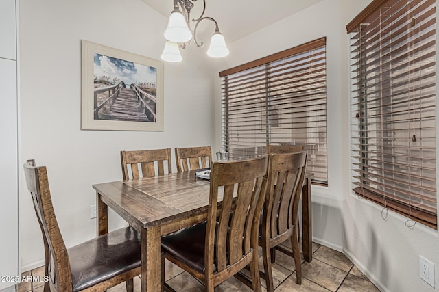 dining area featuring baseboards, light tile patterned flooring, and a notable chandelier