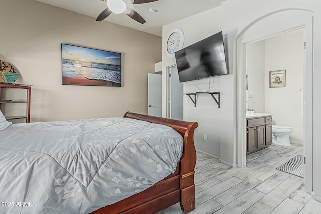 bedroom featuring light wood-style flooring, ceiling fan, and ensuite bath