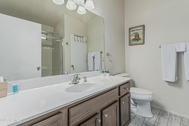 bathroom featuring vanity, baseboards, toilet, and a shower stall