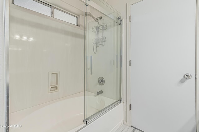 bathroom with bath / shower combo with glass door