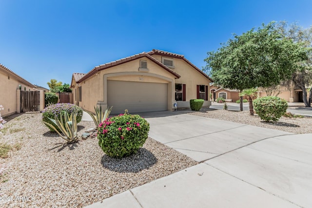 mediterranean / spanish-style home featuring fence, an attached garage, a tile roof, stucco siding, and driveway