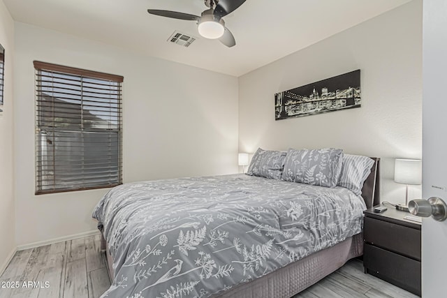 bedroom with baseboards, ceiling fan, wood finished floors, and visible vents