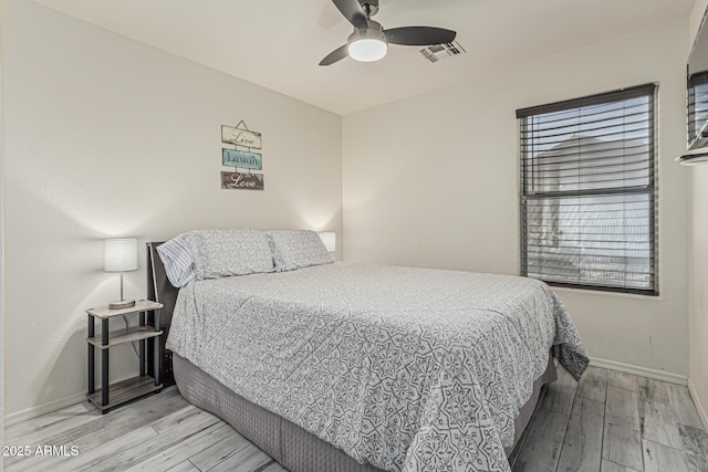 bedroom with visible vents, a ceiling fan, baseboards, and wood finished floors