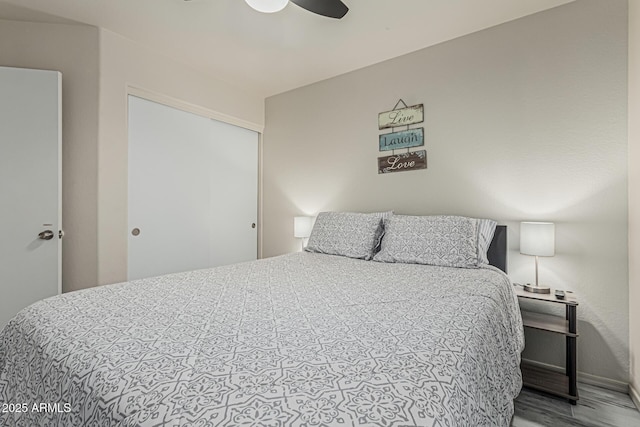 bedroom featuring baseboards, ceiling fan, wood finished floors, and a closet