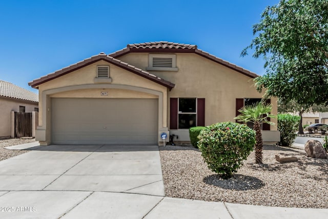 mediterranean / spanish-style house with an attached garage, driveway, a tile roof, and stucco siding