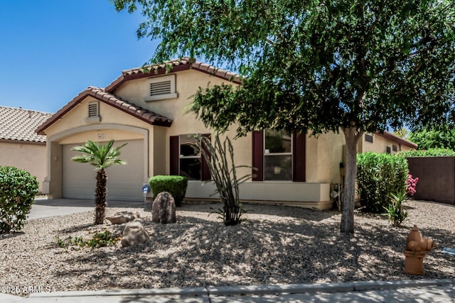 mediterranean / spanish-style house with a garage, stucco siding, driveway, and a tiled roof