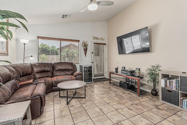 living room featuring ceiling fan, visible vents, beverage cooler, lofted ceiling, and light tile patterned flooring