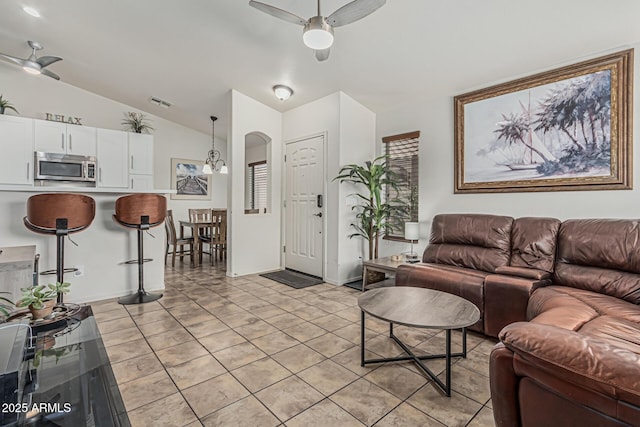living area with visible vents, lofted ceiling, arched walkways, a ceiling fan, and light tile patterned floors