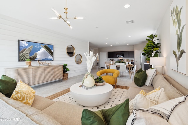 living room featuring light tile patterned floors, a notable chandelier, and wood walls