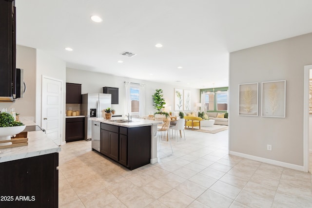 kitchen with appliances with stainless steel finishes, sink, a kitchen island with sink, a notable chandelier, and dark brown cabinets