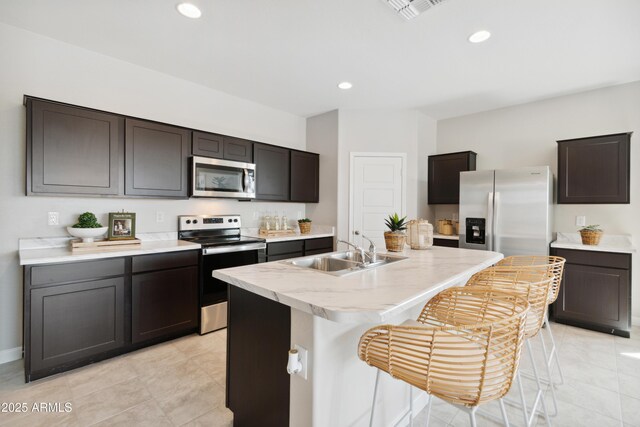 kitchen featuring sink, a breakfast bar area, dark brown cabinets, stainless steel appliances, and an island with sink