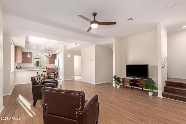 living room featuring ceiling fan with notable chandelier and hardwood / wood-style flooring