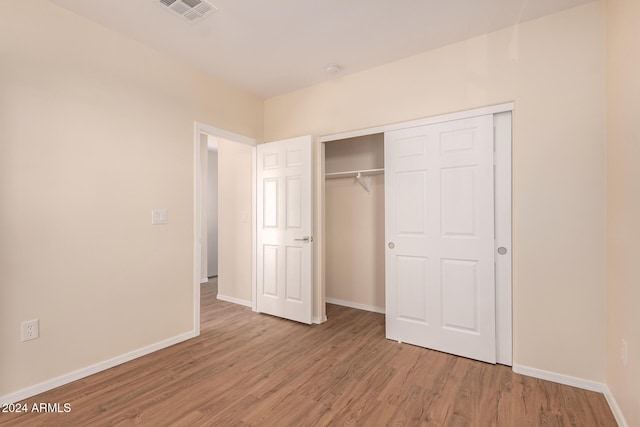 unfurnished bedroom with light wood-type flooring and a closet