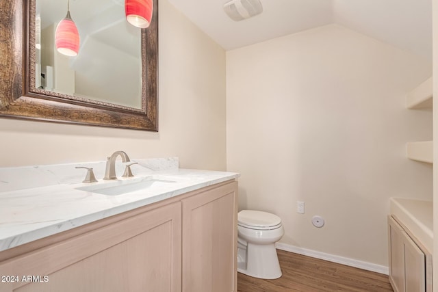 bathroom featuring vanity, toilet, wood-type flooring, and vaulted ceiling