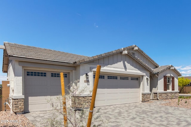12358 W Marguerite Ave, Avondale, AZ 85323 - view of front of house featuring a tiled roof, driveway, stone siding, an attached garage, and stucco siding