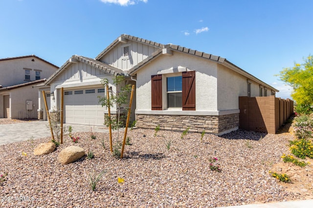 12358 W Marguerite Ave, Avondale, AZ 85323 - view of front of house with driveway, stone siding, fence, an attached garage, and board and batten siding