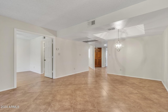 unfurnished room featuring a notable chandelier and a textured ceiling