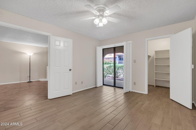 empty room with ceiling fan, a textured ceiling, and light hardwood / wood-style flooring