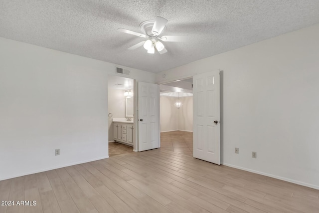 unfurnished bedroom featuring light wood-type flooring, ceiling fan, a textured ceiling, and ensuite bath