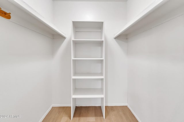 walk in closet with light hardwood / wood-style floors