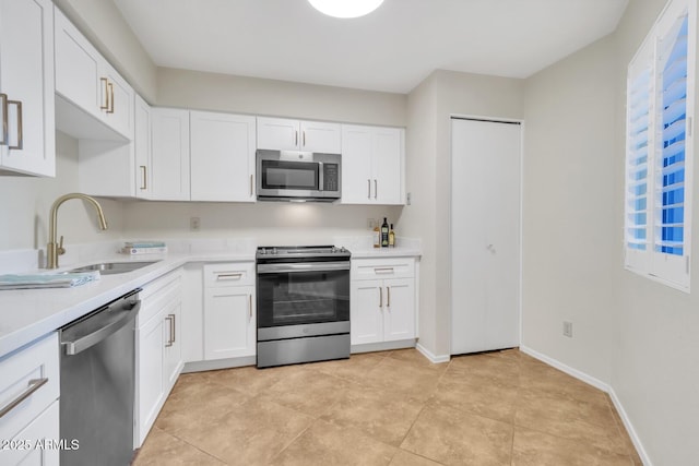 kitchen with light tile patterned floors, sink, white cabinetry, and appliances with stainless steel finishes