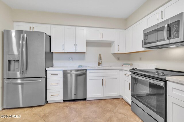 kitchen with sink, white cabinets, appliances with stainless steel finishes, and light tile patterned flooring