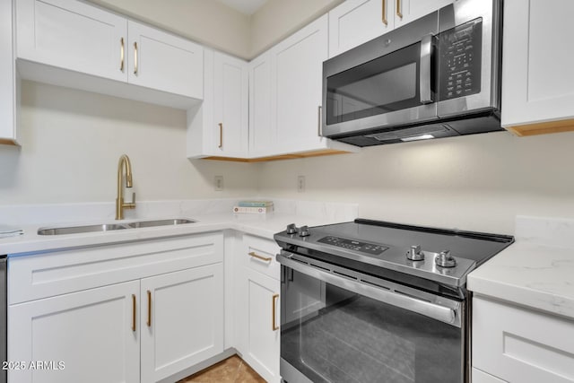 kitchen featuring light stone countertops, white cabinets, appliances with stainless steel finishes, and sink