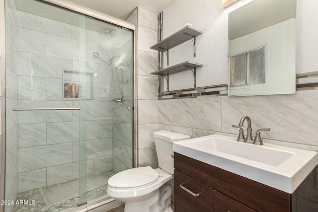 bathroom with vanity, toilet, a shower with shower door, and tile walls