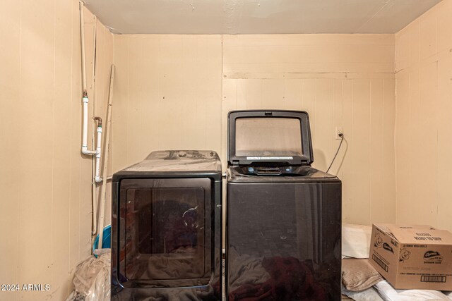 laundry room featuring washer and dryer and wooden walls