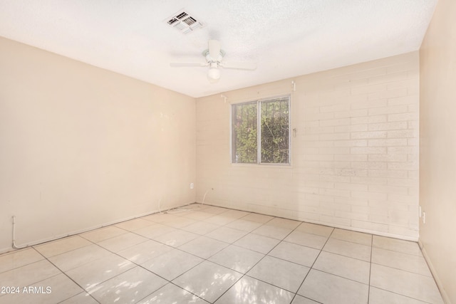 spare room featuring a textured ceiling, ceiling fan, and light tile patterned flooring