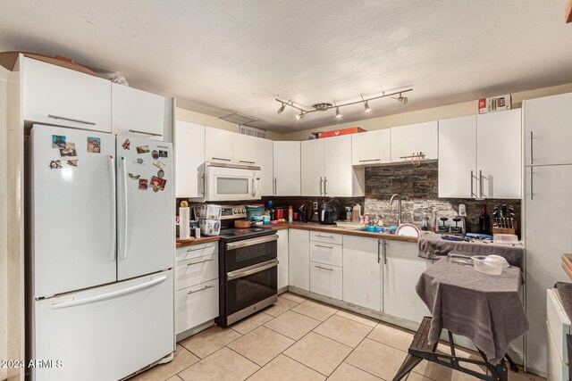 kitchen with a textured ceiling, white appliances, white cabinetry, and sink