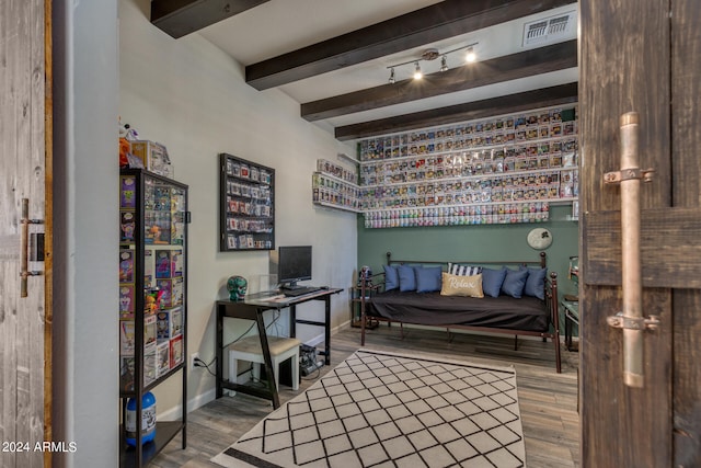 bedroom with beamed ceiling and hardwood / wood-style floors