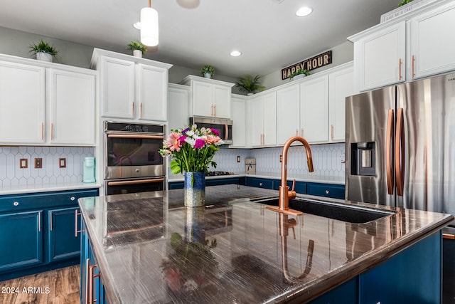 kitchen featuring hanging light fixtures, appliances with stainless steel finishes, white cabinetry, sink, and blue cabinets