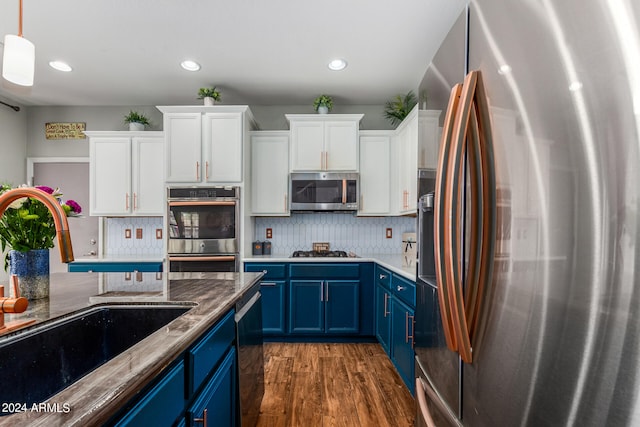 kitchen featuring dark hardwood / wood-style floors, blue cabinets, pendant lighting, appliances with stainless steel finishes, and sink